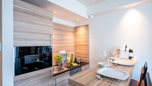 Een moderne keuken met houten kastjes, een inbouwoven en een eethoek met een witte tafel gedekt voor twee personen.