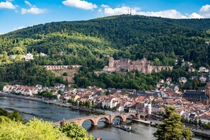 Une ville historique traversée par une rivière, avec un pont et un château perché sur une colline.