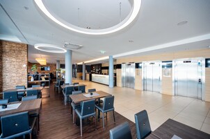 Un moderno vestíbulo de hotel con una recepción central, zona de estar y una fila de ascensores.