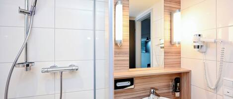 A modern bathroom with a glass-enclosed shower, a wooden vanity, a large mirror, and a white sink.