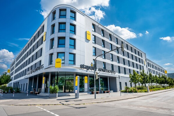 Un bâtiment moderne à la façade incurvée, doté de grandes fenêtres et d’une enseigne indiquant « Staycity Apartments ».