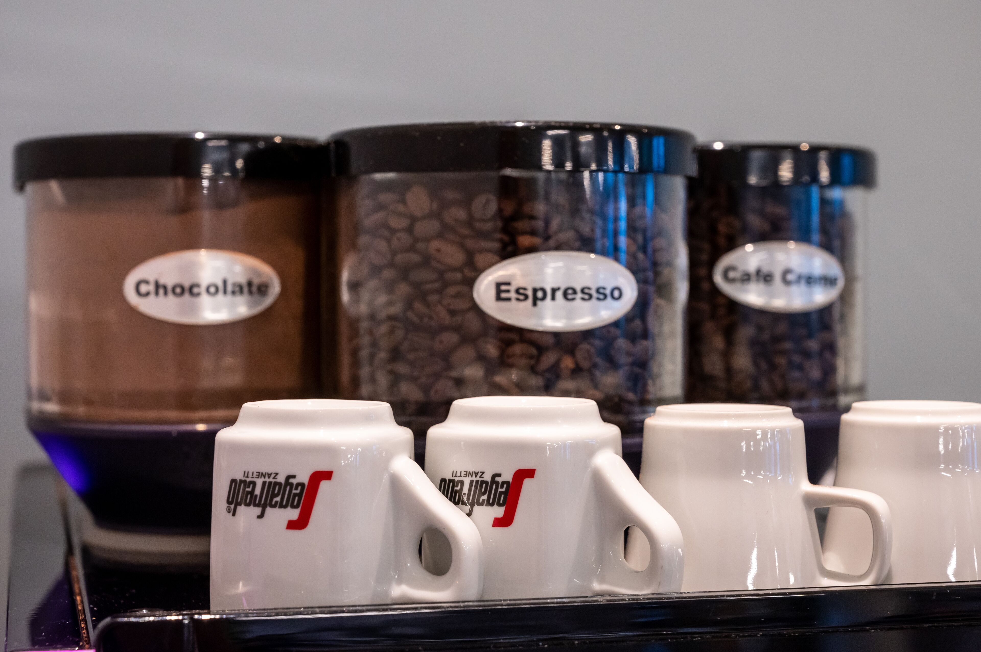 Een koffiehoek met containers met labels voor chocolade, espresso en cafe crema.