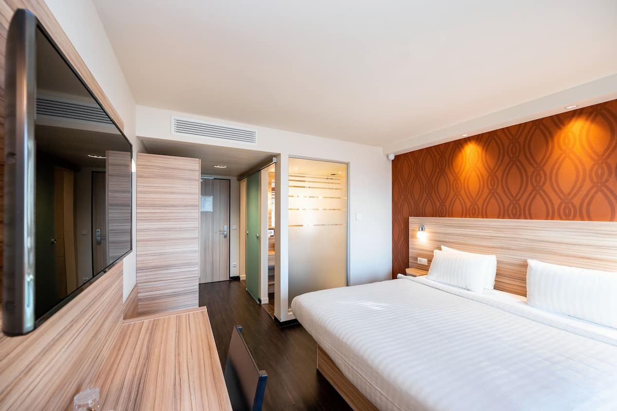 Une chambre d’hôtel moderne dotée d’un grand lit, d’un téléviseur à écran plat et d’une armoire.