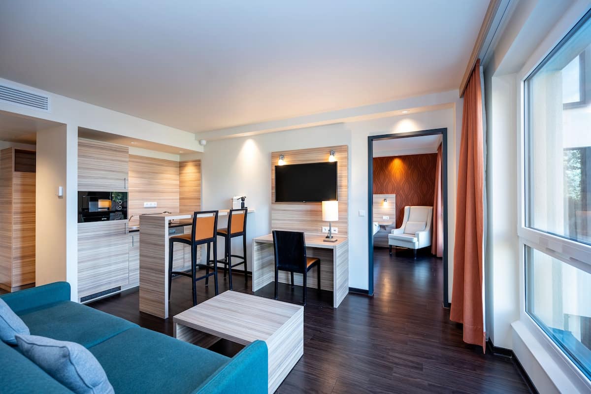 Une chambre d’hôtel moderne comprenant un coin salon, une kitchenette et une chambre à coucher séparée.