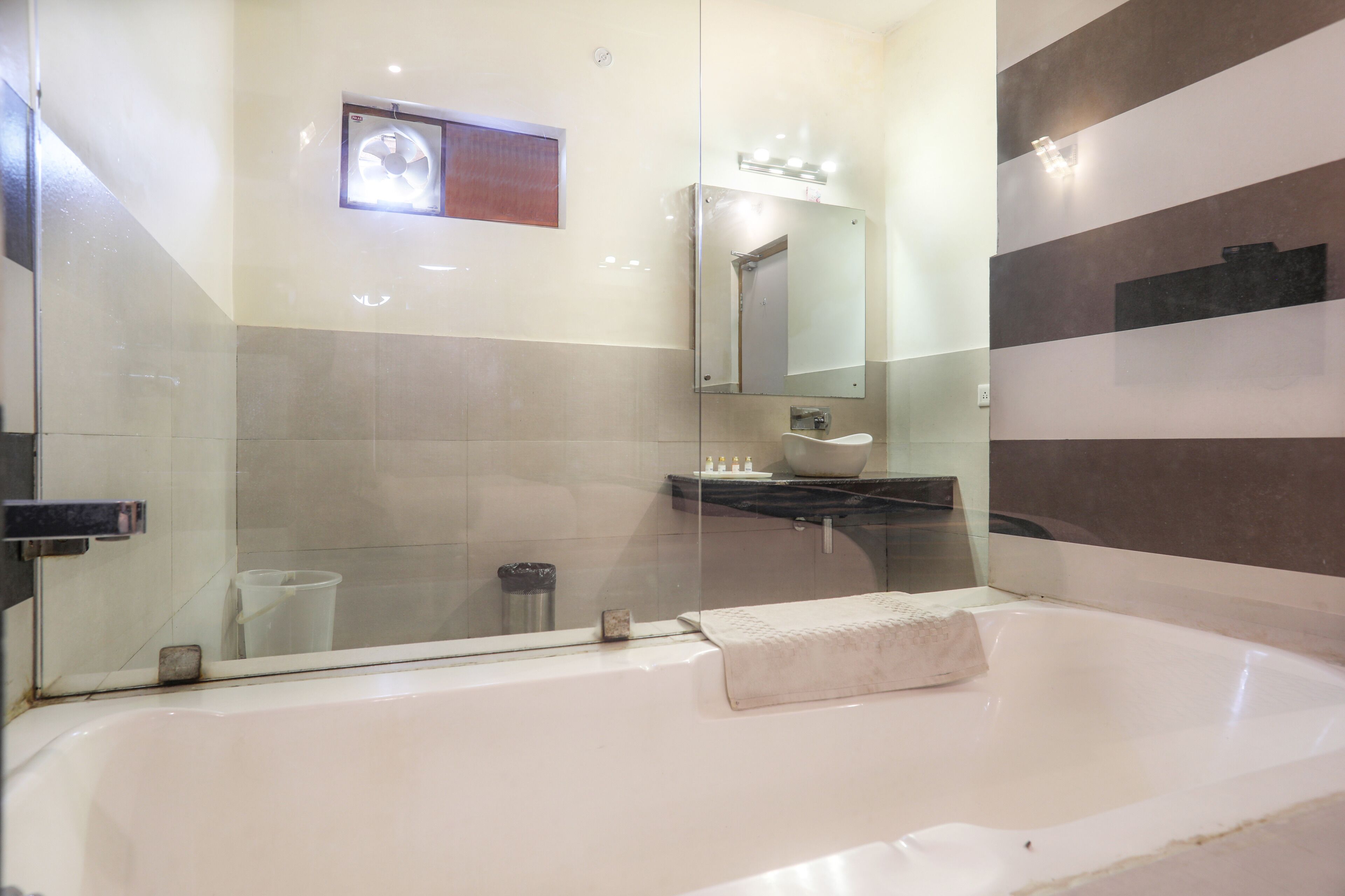 A modern bathroom with a glass shower enclosure, a large bathtub, and a vanity with a mirror.