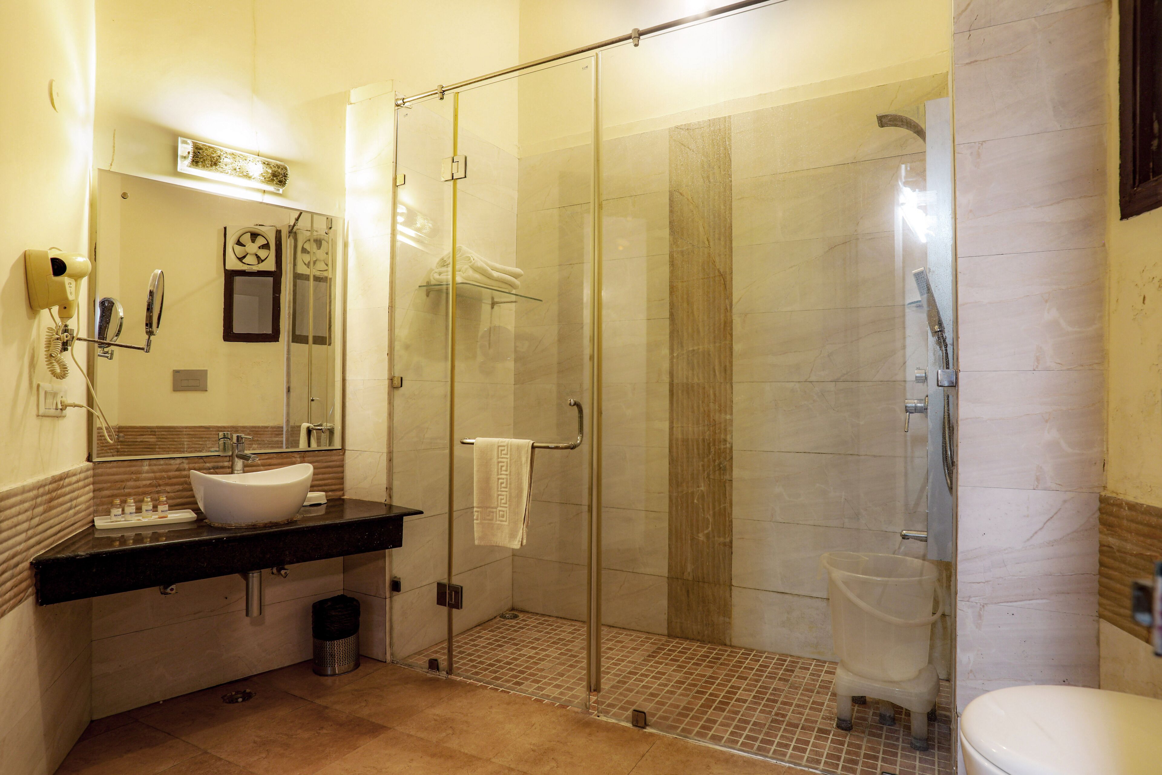 A modern bathroom with a glass-enclosed shower, a white sink, and a vanity with toiletries.