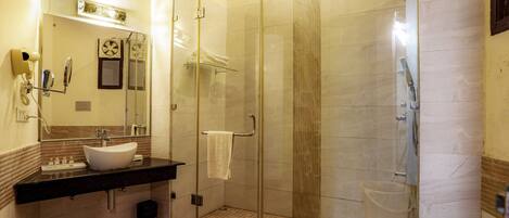 A modern bathroom with a glass-enclosed shower, a white sink, and a vanity with toiletries.