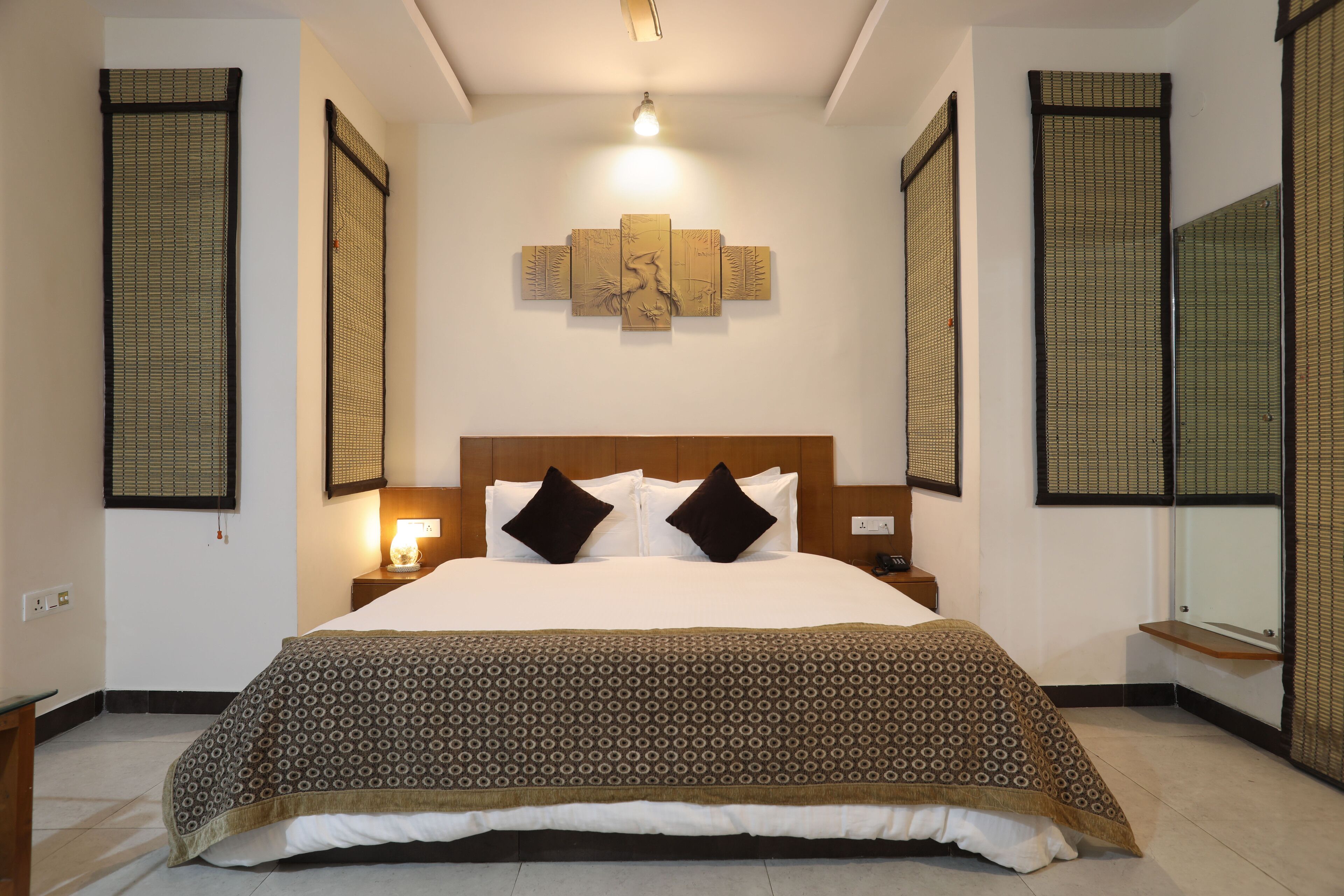 A neatly made bed with a patterned bedspread, a headboard with two pillows, and a wall-mounted artwork above it.