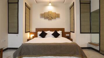 A neatly made bed with a patterned bedspread, a headboard with two pillows, and a wall-mounted artwork above it.