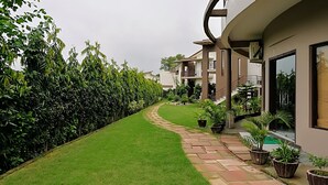 Ein gepflegter Garten mit einem geschwungenen Weg, der zu einem Gebäude mit mehreren Balkonen und einer Treppe führt.