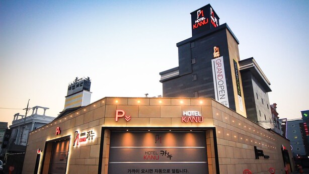 A hotel with a prominent 'HOTEL KANU' sign, a parking sign, and a 'GRAND OPEN' sign indicating a new opening. - Kanu Hotel (Jeonju)