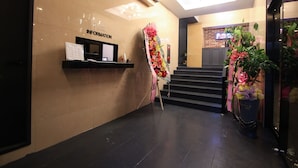 A reception area with a reception desk, a staircase, and potted plants. - Kanu Hotel (Jeonju)
