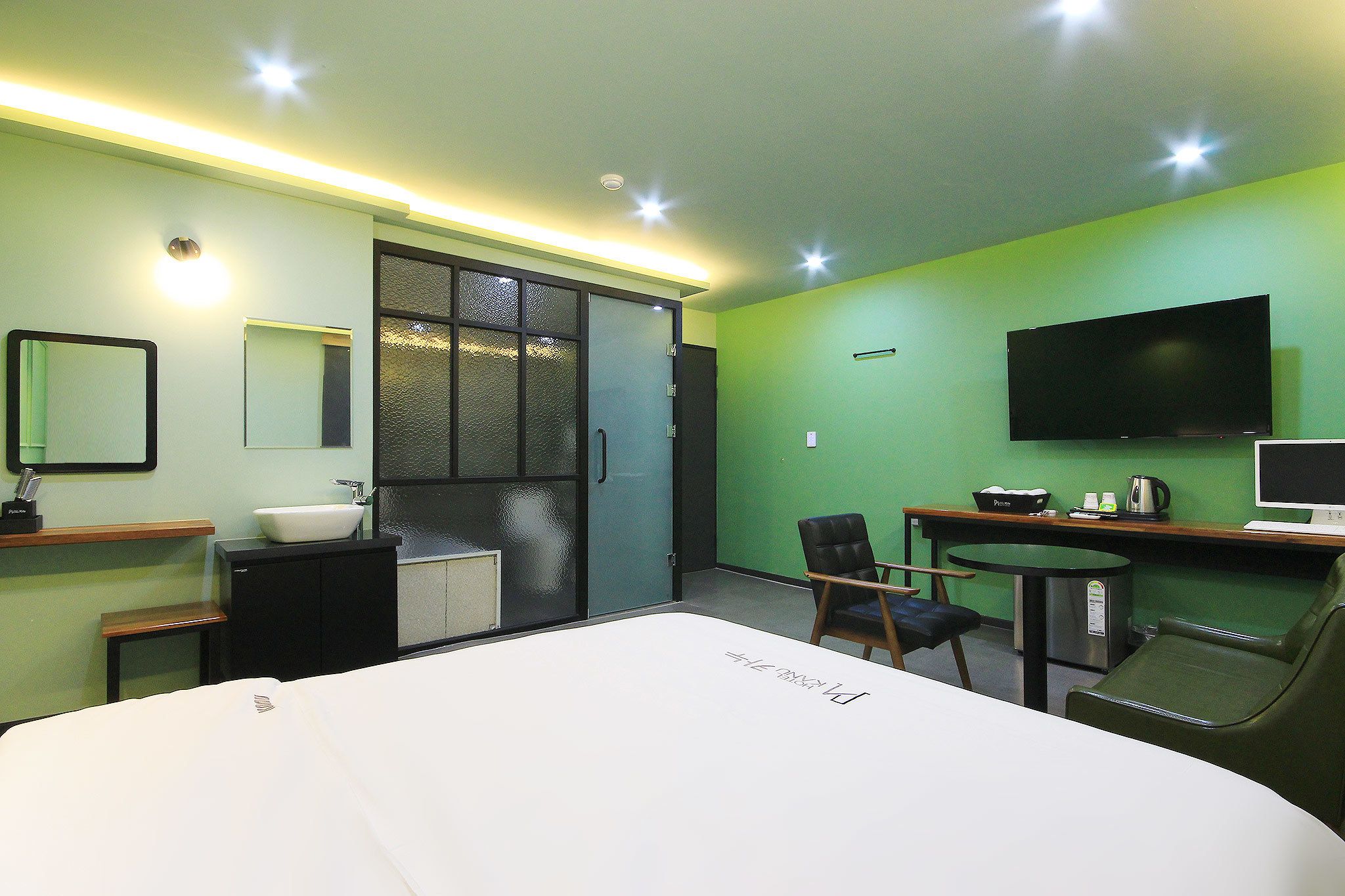 Habitación de hotel con cama, escritorio con silla, televisor, mesita y ventana con vistas.