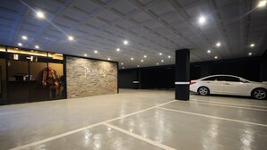 A parking garage with a white car parked in the right lane. - Kanu Hotel (Jeonju)