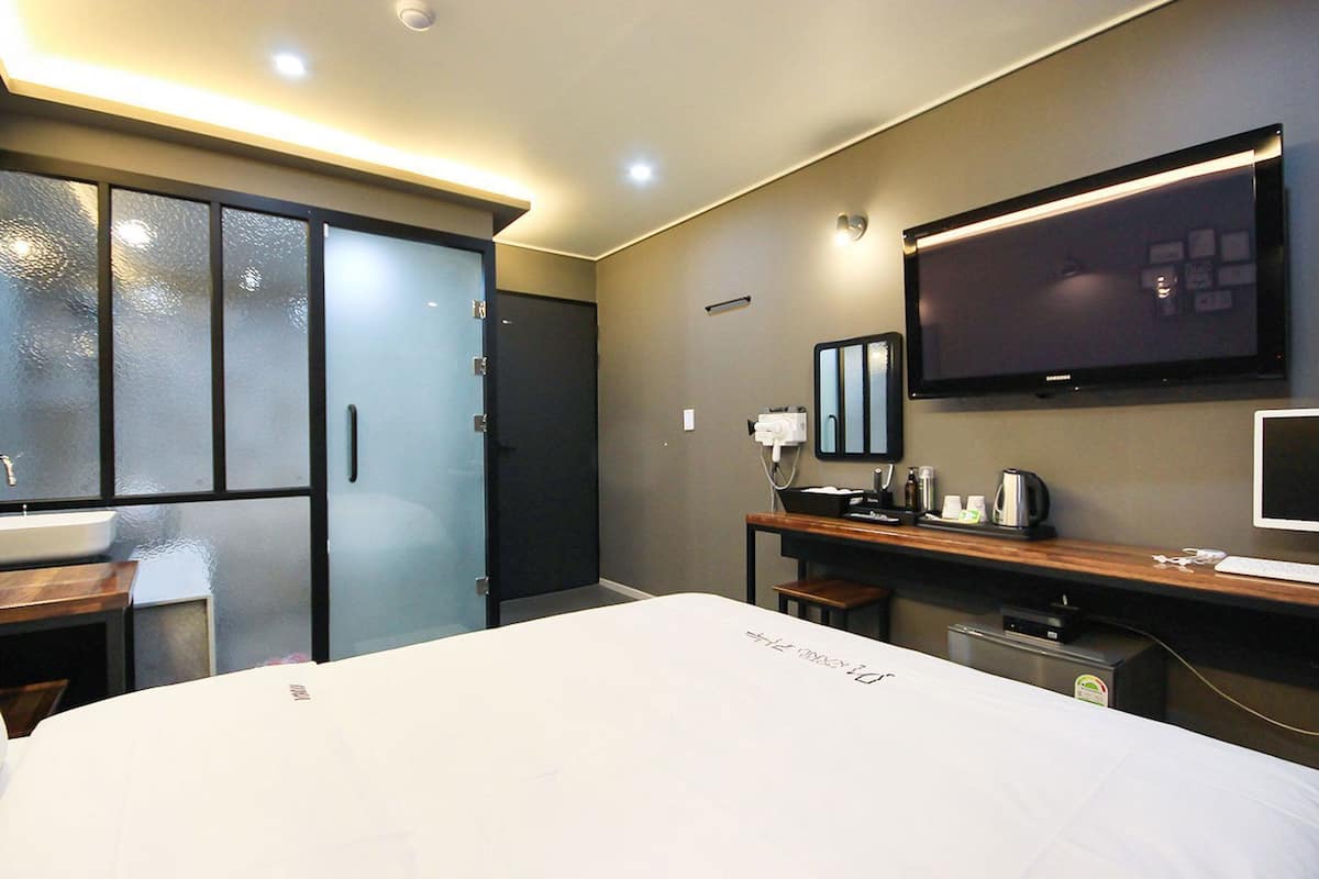 Habitación de hotel con cama, escritorio, televisión y minibar.