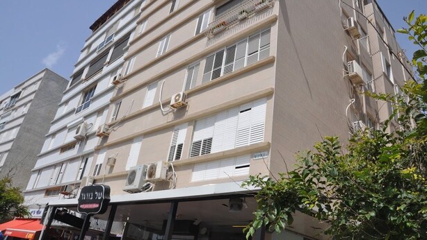 A multi-story building with balconies, air conditioning units, and a visible storefront at the ground level. - Isra Home Apartment Ben Gurion 141 (Bat Yam)