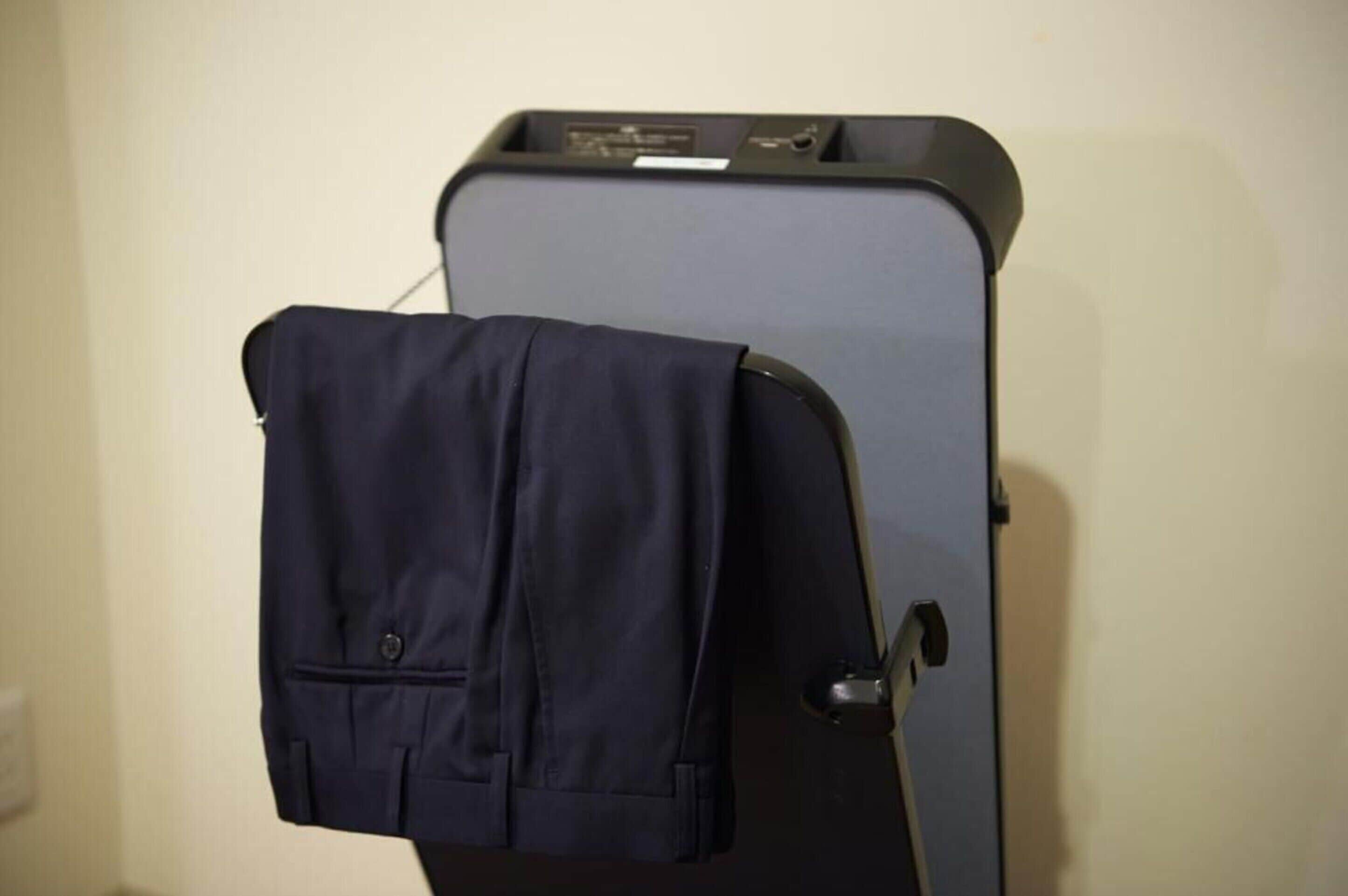 A suitcase with a jacket hanging on the side of a black suitcase.