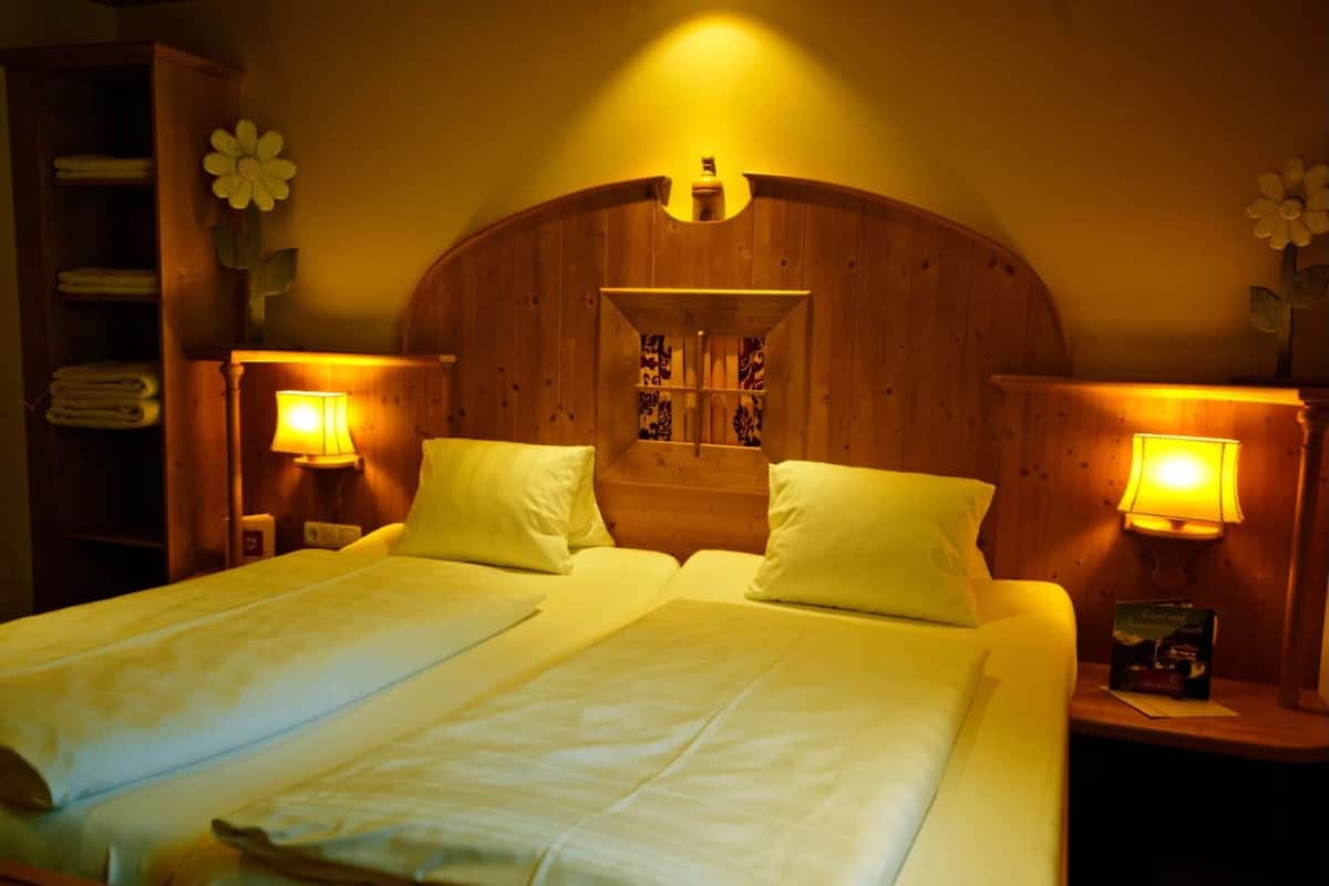 Ein Doppelbett mit zwei Kissen, einem Holzkopfschild und zwei Nachttischlampen.