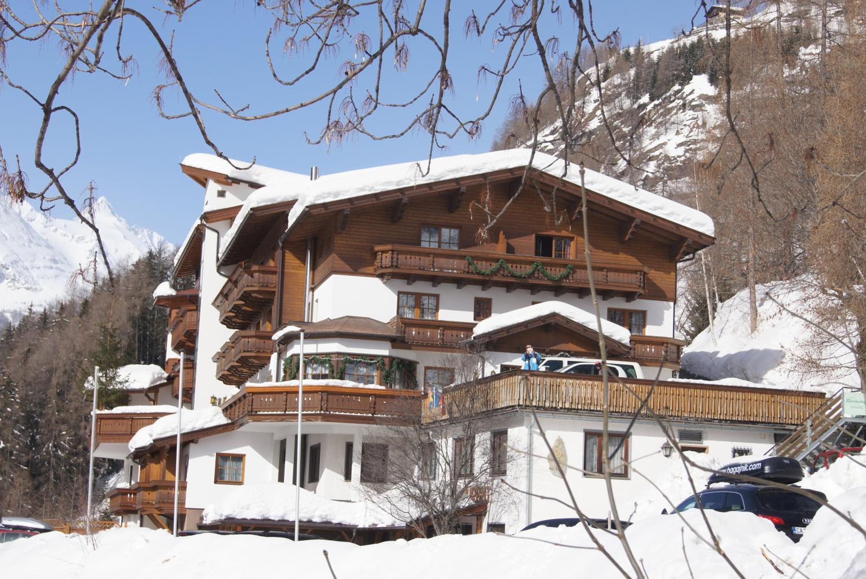 A multi-story chalet with a wooden exterior, snow-covered roof, and balconies.