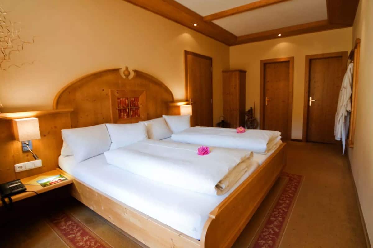 Ein Doppelzimmer mit zwei Betten, einem Holz-Kopfteil, Nachttischlampen und einem roten Teppich.