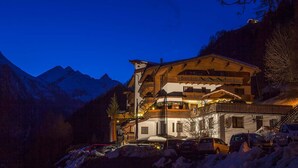 Un hotel de varios pisos con fachada de madera, balcones y vistas a montañas nevadas.