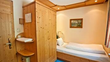 Une petite pièce agréable, avec une armoire en bois, un lit simple et une petite étagère.