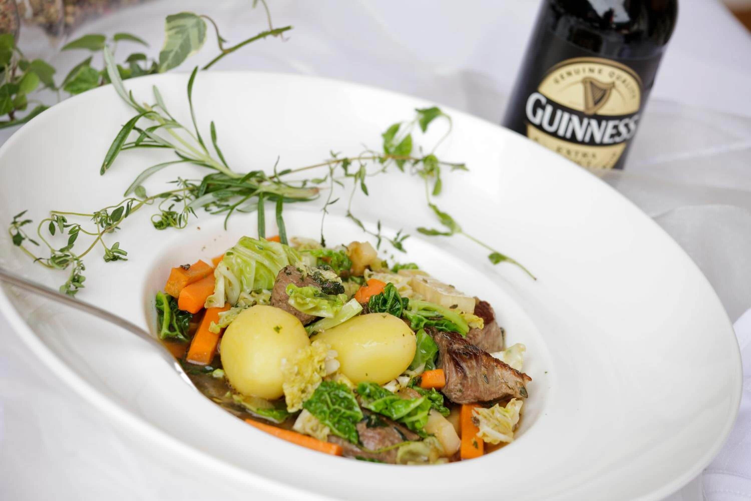 Prato de comida com diversos vegetais e carne, acompanhado por uma garrafa de cerveja Guinness.
