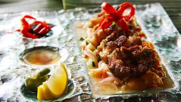 A meal with grilled meat, vegetables, and a red garnish on a glass plate.