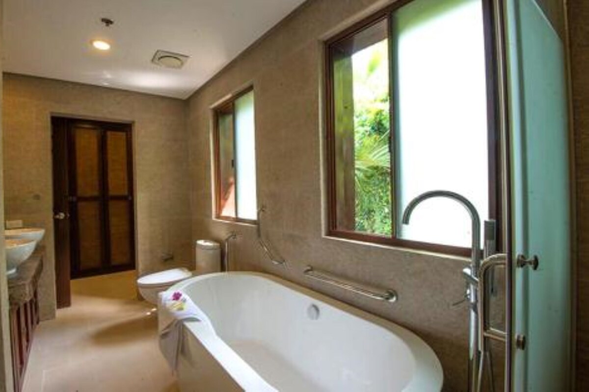 A bathroom with a freestanding bathtub, a sink, a toilet, and a window with a view of greenery.