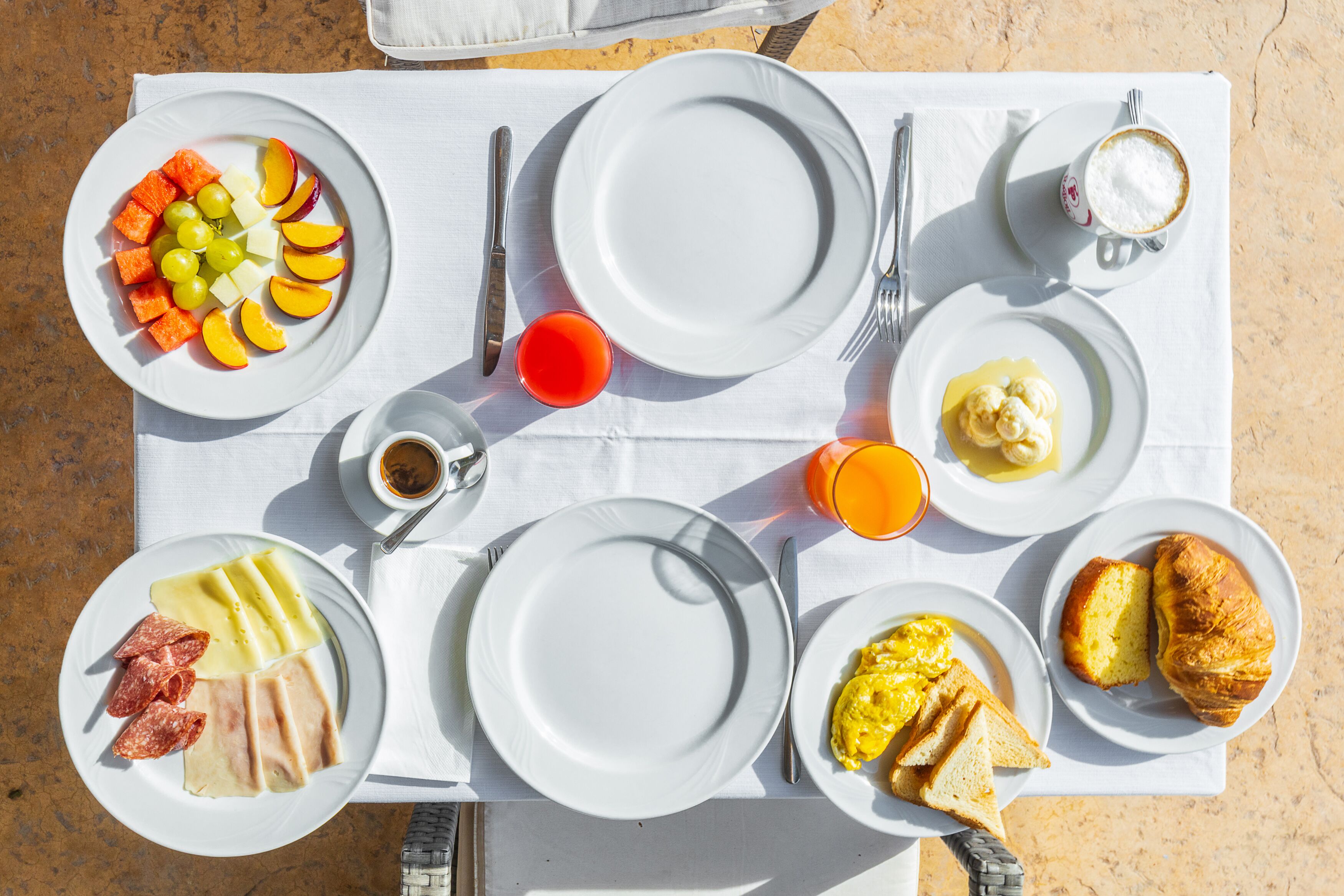 A breakfast table with plates of food, including eggs, toast, and fruit.