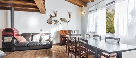 Un salon chaleureux avec un plafond en bois, une cheminée, un canapé et une table à manger avec des chaises.