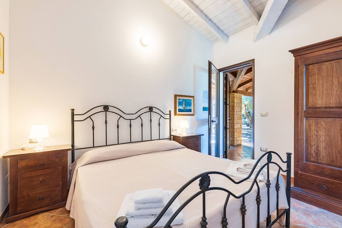 A bedroom with a bed, wooden nightstand, and a wooden wardrobe.