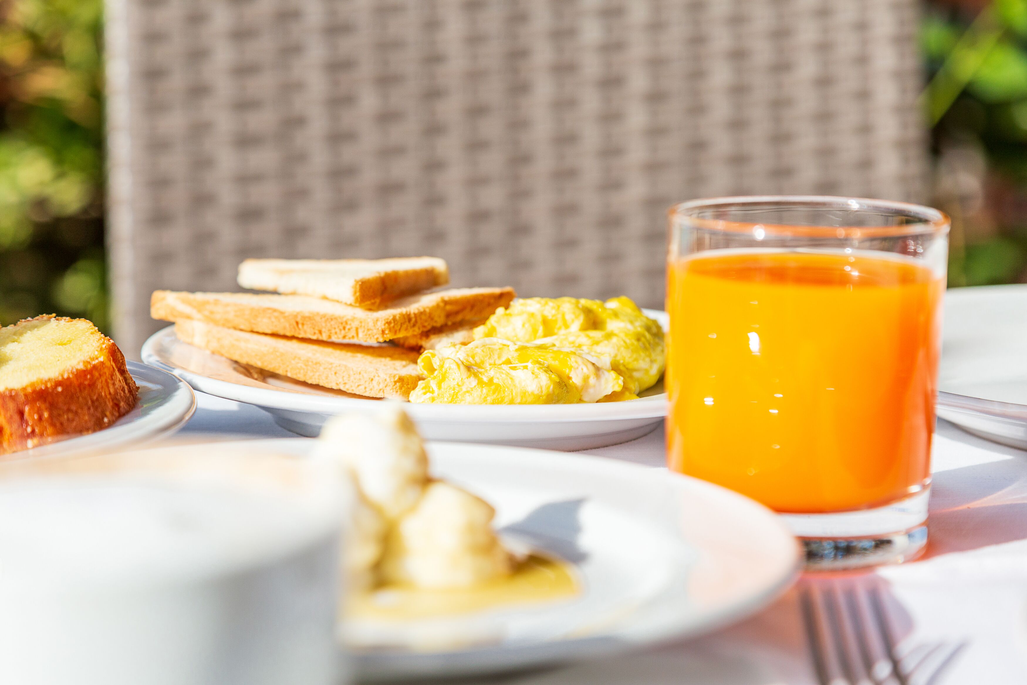 A breakfast setting with toast, scrambled eggs, and orange juice on a table.