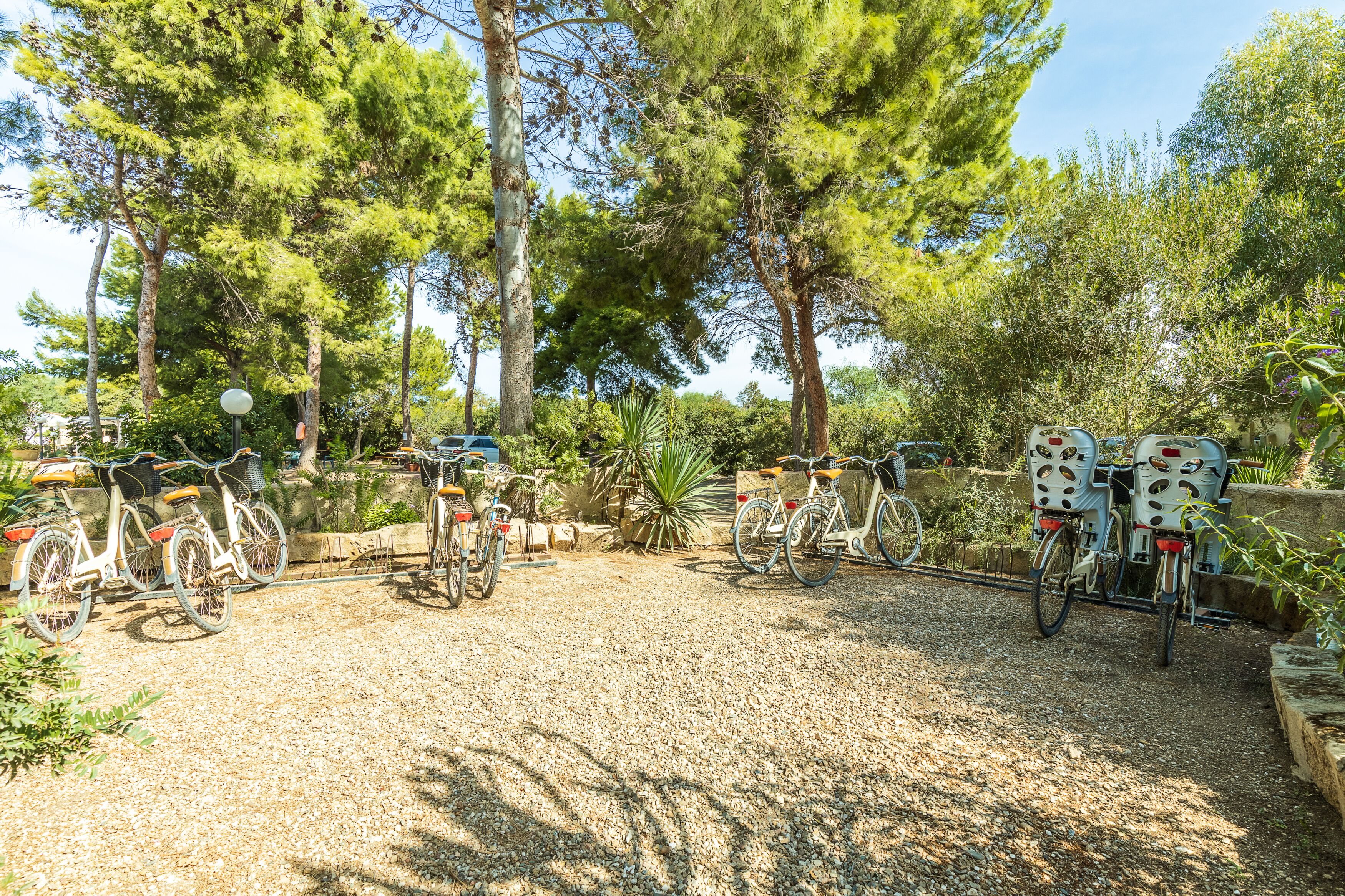 A gravel parking area with bicycles and a bike rack.