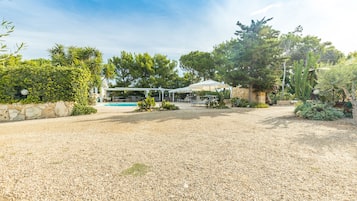 Un jardin avec une piscine, un espace salon abrité et diverses plantes.