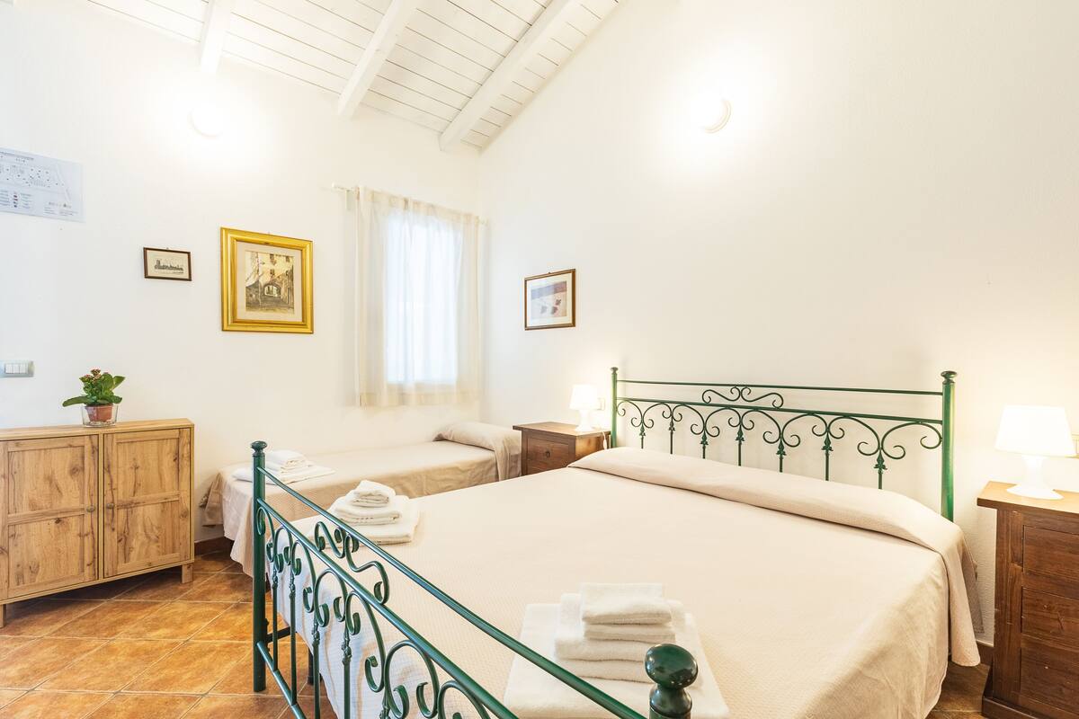 A room with two beds, a wooden cabinet, and a window with curtains.