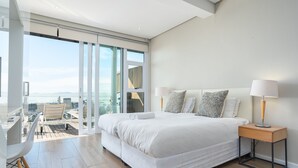 A modern bedroom with a large bed, a nightstand, a desk, and a chair. - High Level 1 (Cape Town)