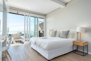 Une chambre à coucher moderne avec un grand lit, une table de chevet, un bureau et une chaise.