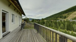 Una terraza de madera con barandilla que da a un paisaje montañoso.