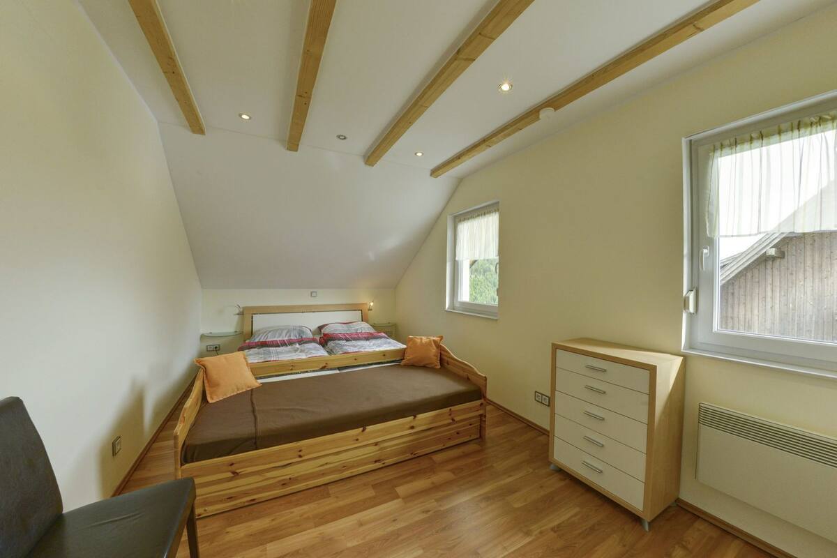 Een slaapkamer met een hoogslaper, een bureau en een raam.