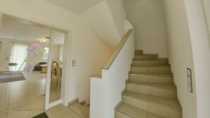 Una escalera con peldaños color beige y barandilla, que conduce a un piso superior.