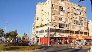 Un hotel de varios pisos con un letrero de Coca-Cola, un supermercado y una máquina expendedora de Coca-Cola a la vista.