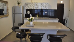 Una cocina moderna con una isla central, sillas negras, un refrigerador, una estufa y un lavaplatos.
