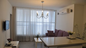 Una sala de estar moderna con una mesa de comedor, sofá y televisor montado en la pared.