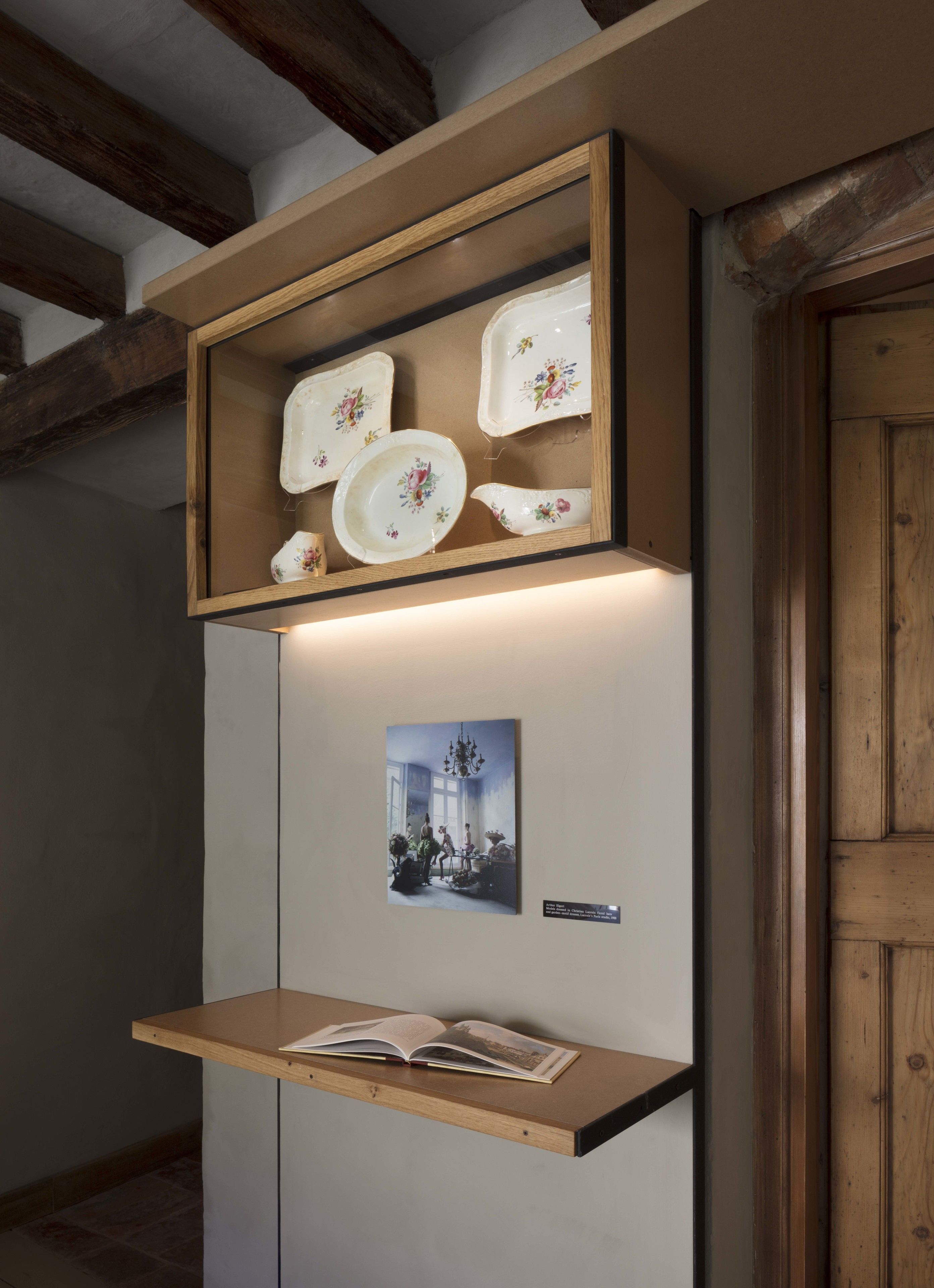 A wooden shelf with decorative plates and a framed photograph.