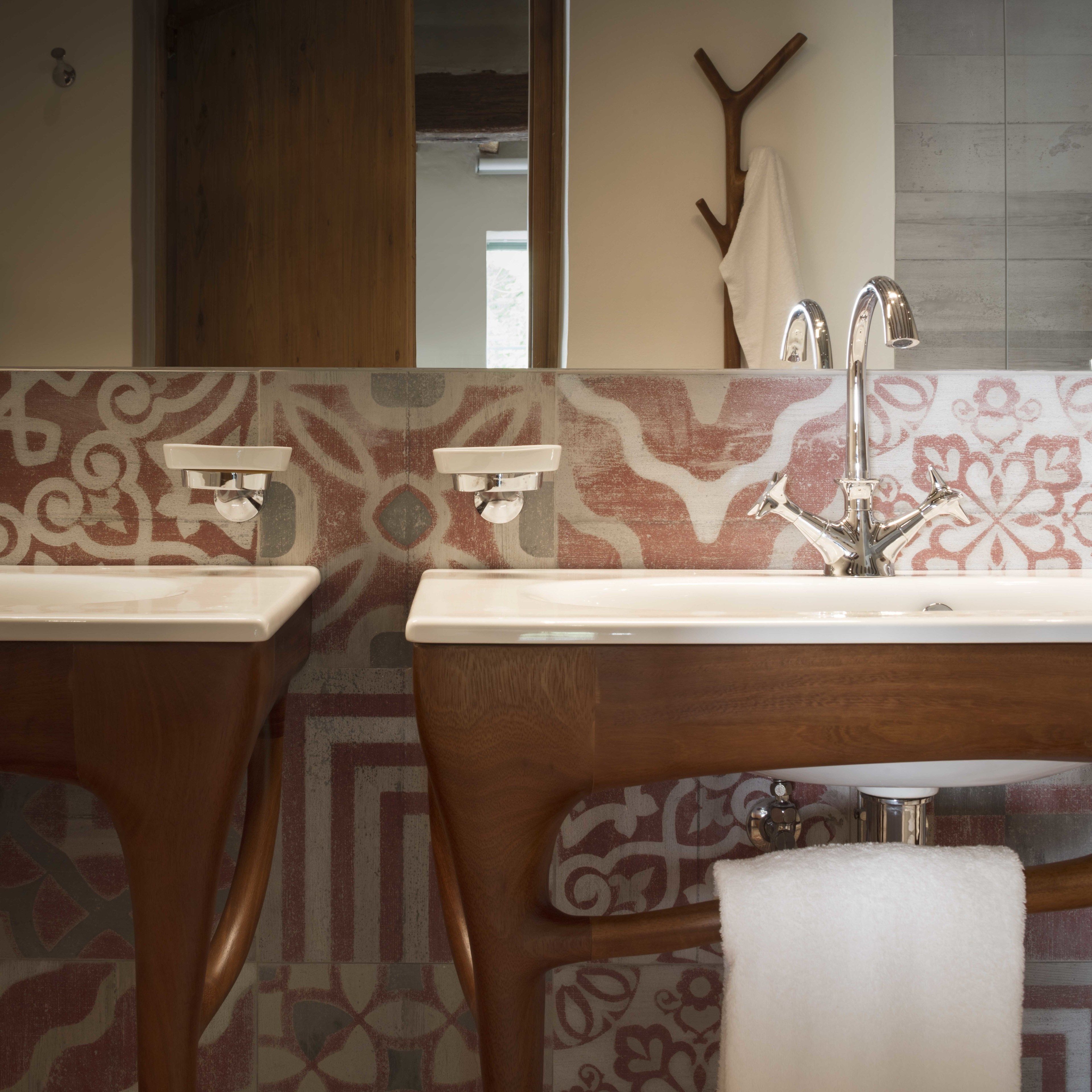 A bathroom with two sinks, a towel rack, and patterned tiles.