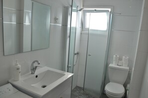 A modern bathroom with a glass-enclosed shower, a sink with a mirror, and a toilet.
