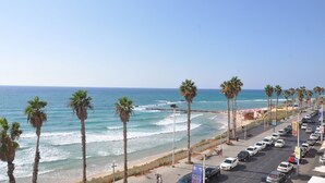 A coastal road lined with palm trees and a beach in the background. - Isra Home Apartments Ben Gurion 81 (Bat Yam)
