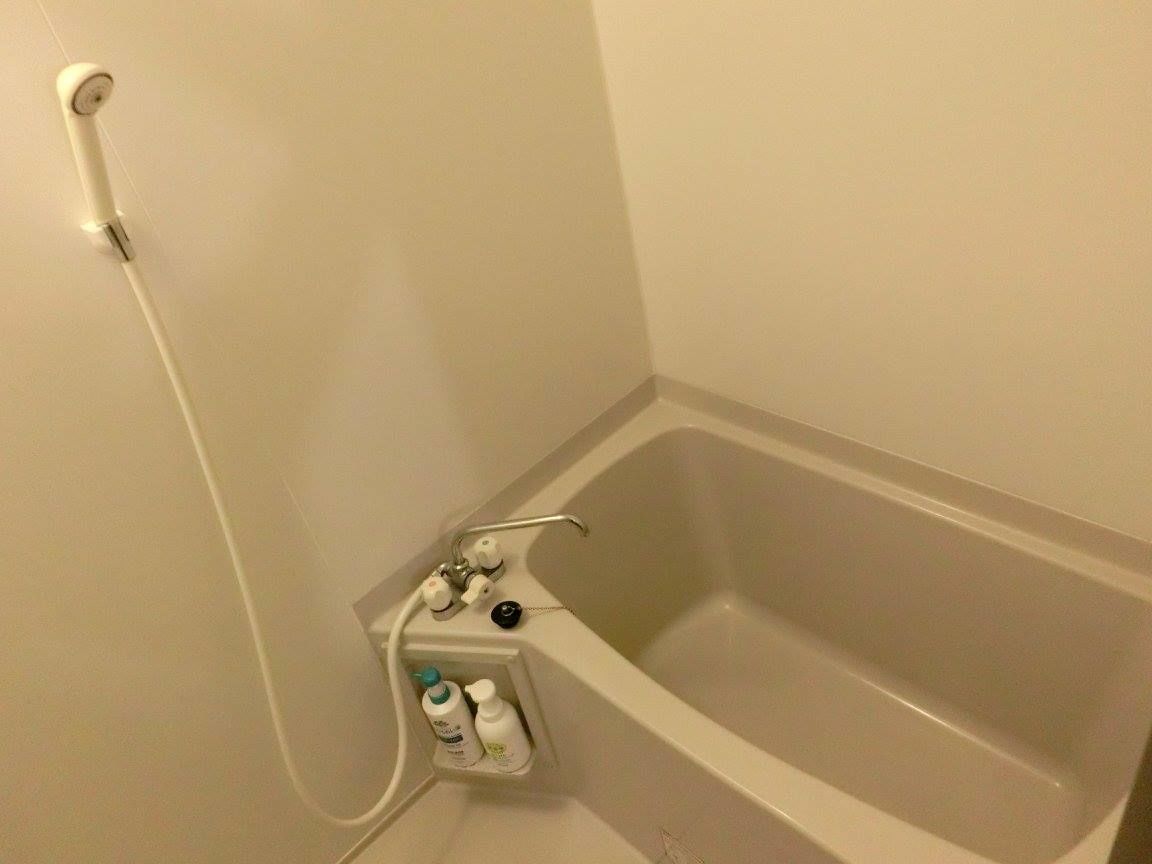 Une salle de bain équipée d’une baignoire, d’une douche et d’une étagère où sont rangés les articles de toilette.