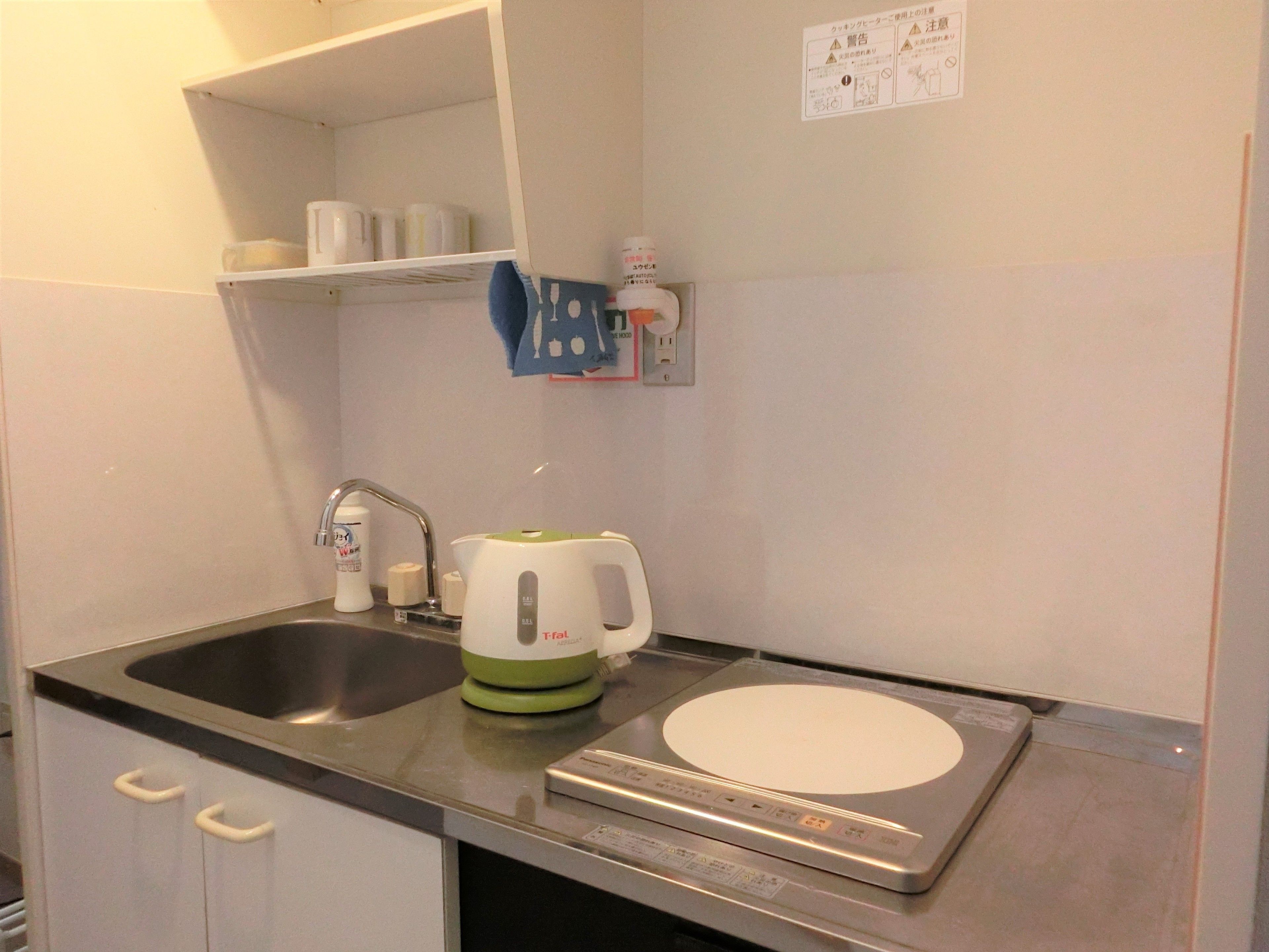 A compact kitchen with a sink, a kettle, and a rice cooker.